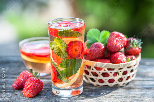 A glass of detox water. Strawberry, lemon and mint with cool clean water, backdrop of a green garden. Detox, diet, Cookery, sports, proper nutrition, sports nutrition, body cleansing