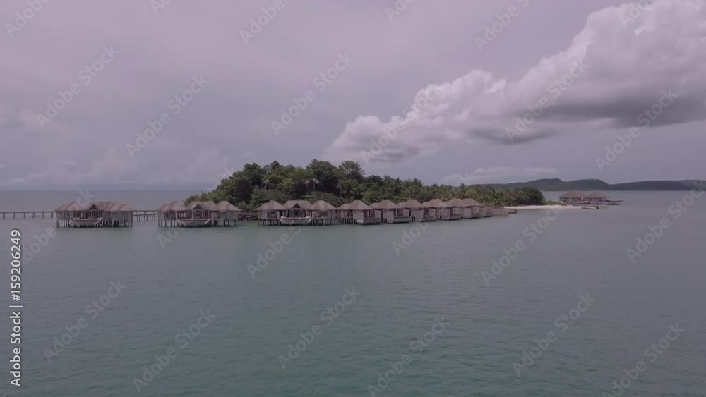 Aerial drone shot - low flying towards the luxury resort and bungalows on a tropical island. Aerial drone shot - low flying towards the luxury resort and bungalows on a tropical island.