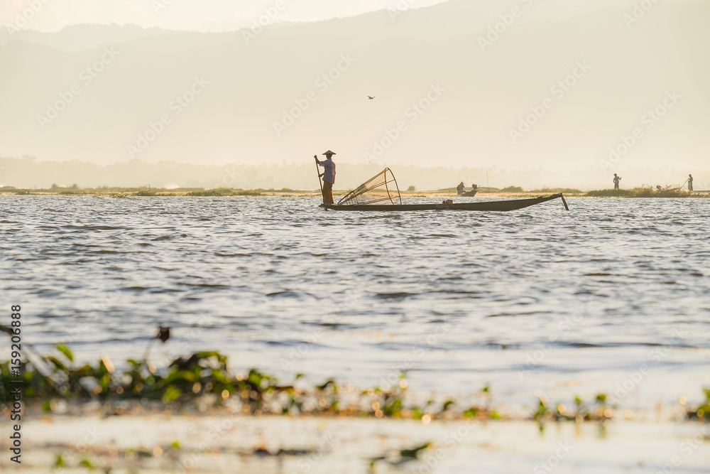 Inle Lake, Myanmar - December 7, 2014: Burmese fishermen on boat with fishing net at Inle lake in Myanmar (Burma)