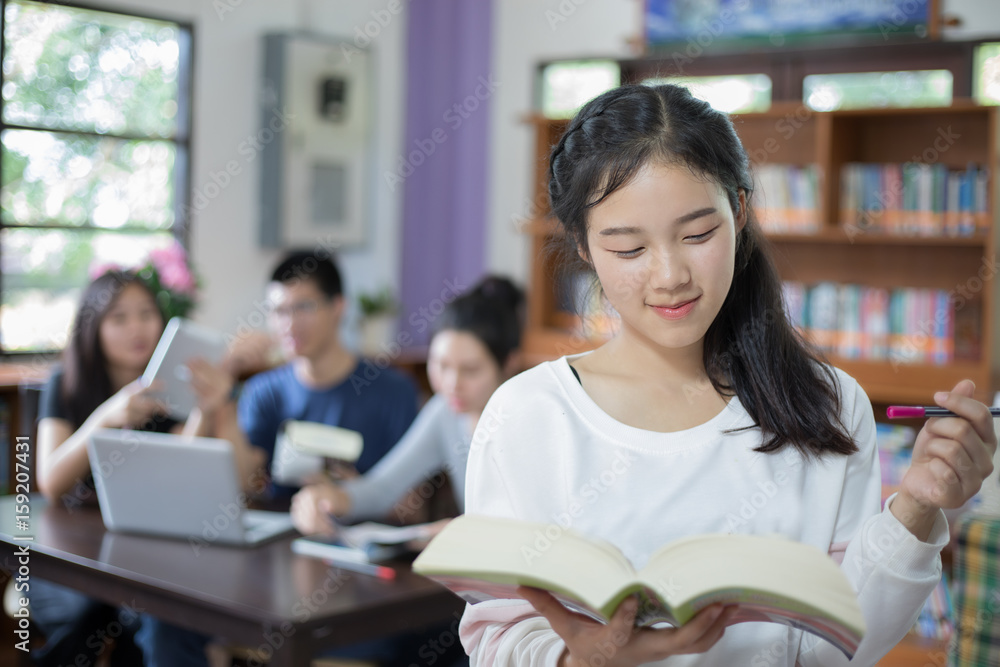 Asian female students holding for selection Book in library Asian female students holding for selection Book in library