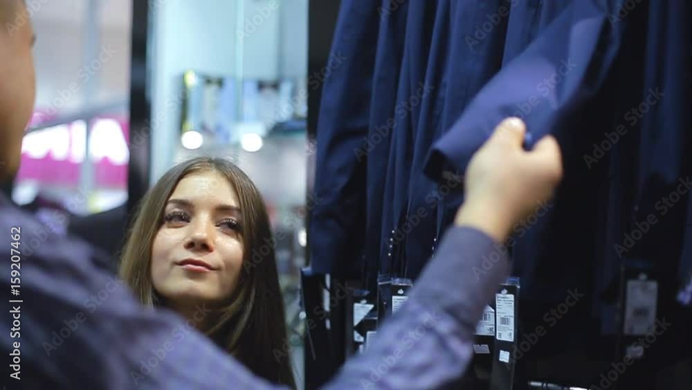 Young couple choose a jacket in the store. Loving guy and girl buy clothes in the store Young couple choose a jacket in the store. Loving guy and girl buy clothes in the store