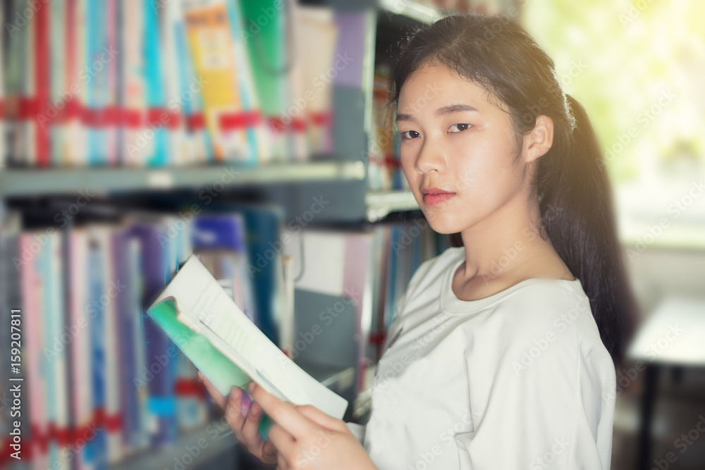 Asian female students holding for selection Book in library Asian female students holding for selection Book in library
