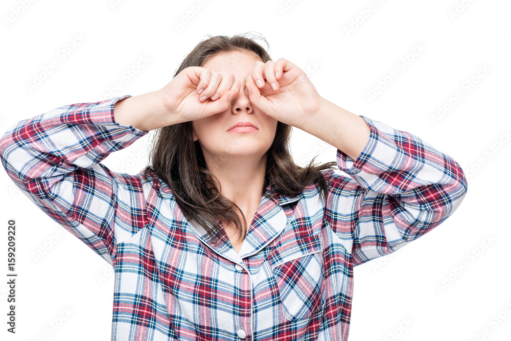 Girl after waking rubbing eyes with hands from bright light on white background Girl after waking rubbing eyes with hands from bright light on white background