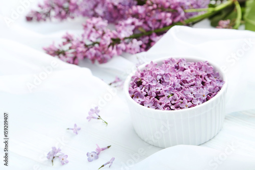 Lilac flowers in bowl on white cloth