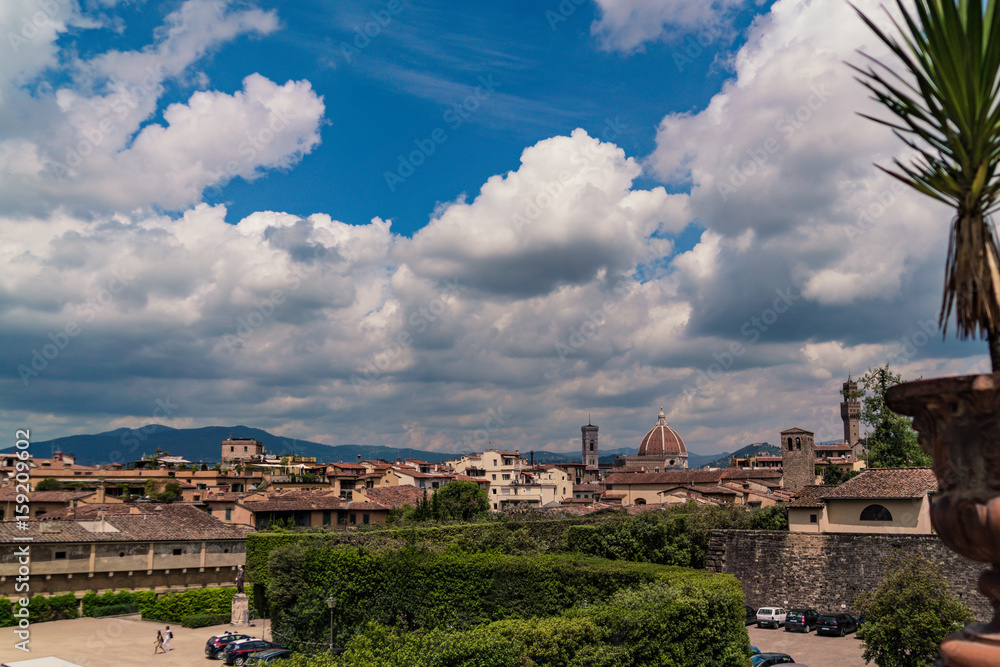 The skyline of Florence seen from the Boboli Gardens with puffy clouds in the sky.