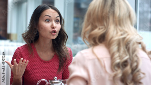 Two young women argue in cafe