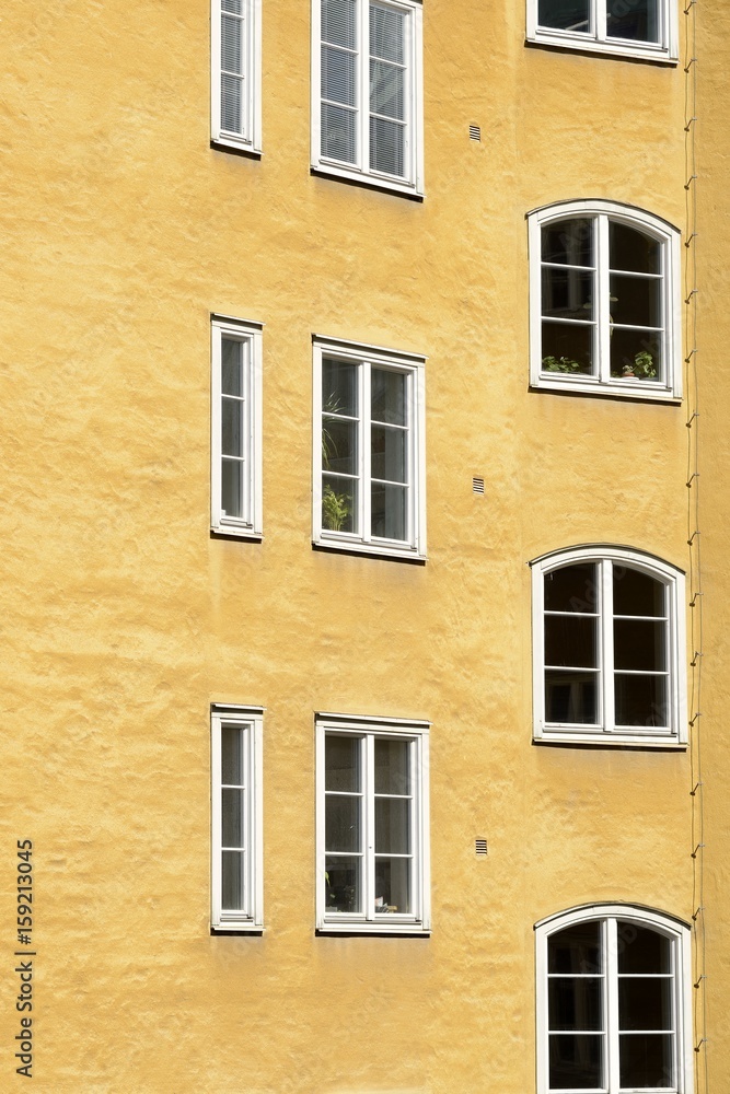 Close up of an apartment building. White windows on a yellow facade.