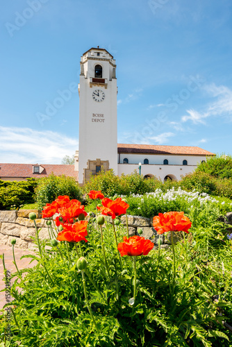 Clock tower of a train depot with bright orange poppies