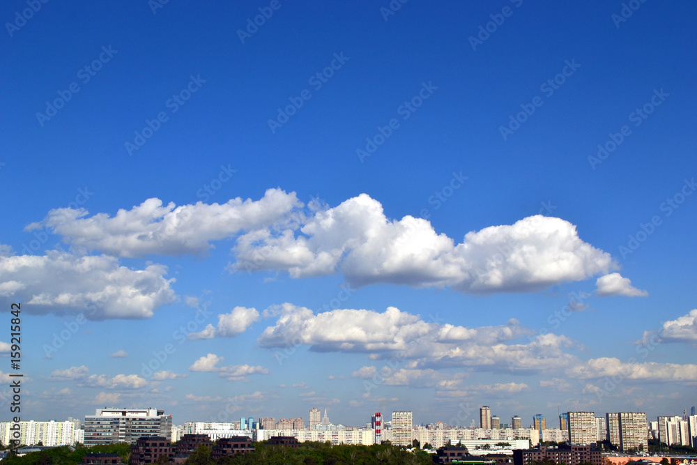 Fluffy clouds over the city in a clear sky