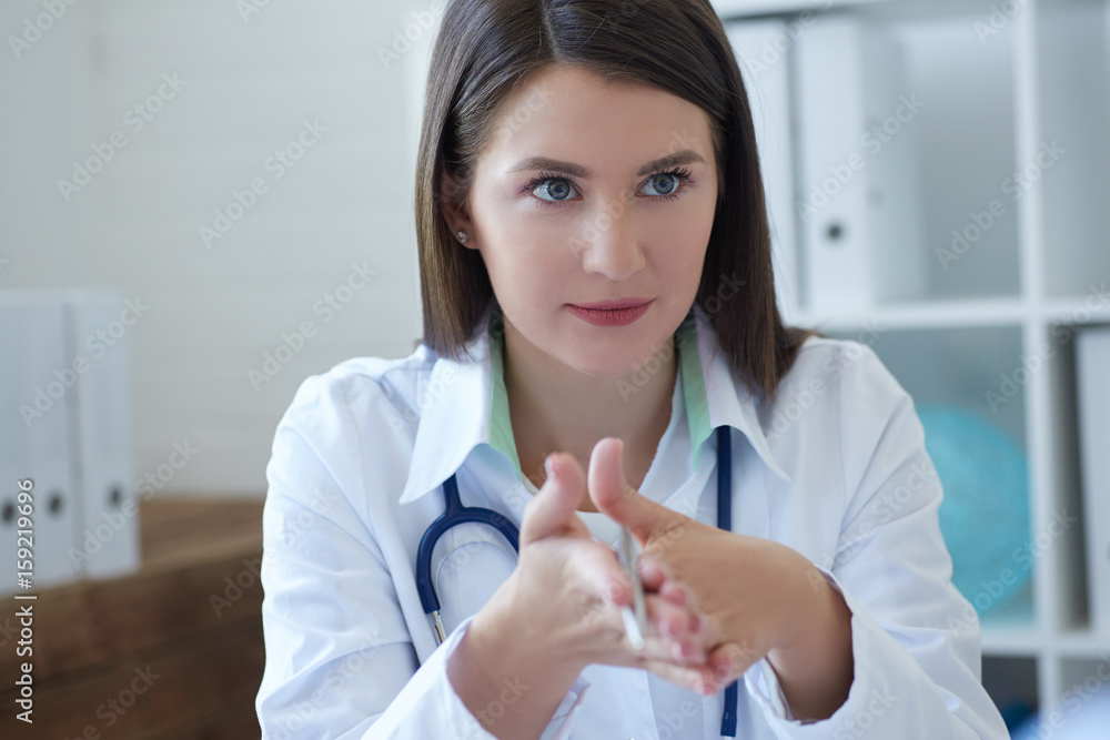 Female doctor wearing coat attending to her patient in a consultation while sitting in a desktop Female doctor wearing coat attending to her patient in a consultation while sitting in a desktop