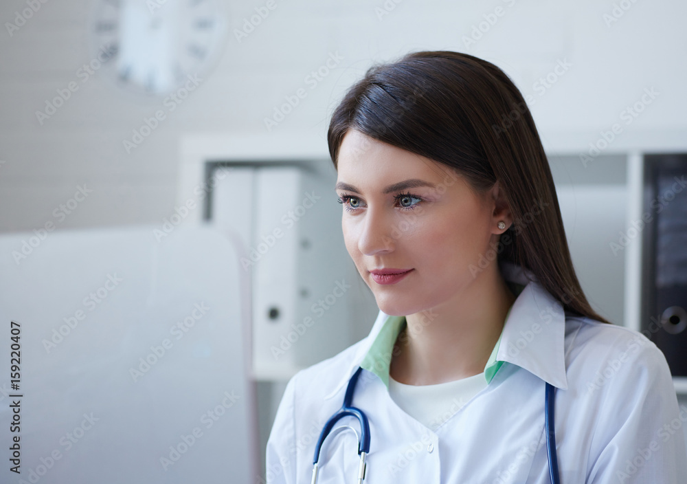 Beautiful female medicine doctor sitting at the table and looking at desktop computer screen. Beautiful female medicine doctor sitting at the table and looking at desktop computer screen.