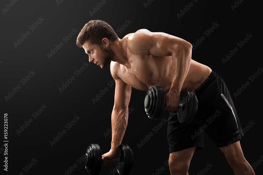 Horizontal studio shot of a young muscular handsome sportsman lifting weights exercising on black background sport lifestyle strength masculinity athletics sexy shirtless power endurance bodybuilding.