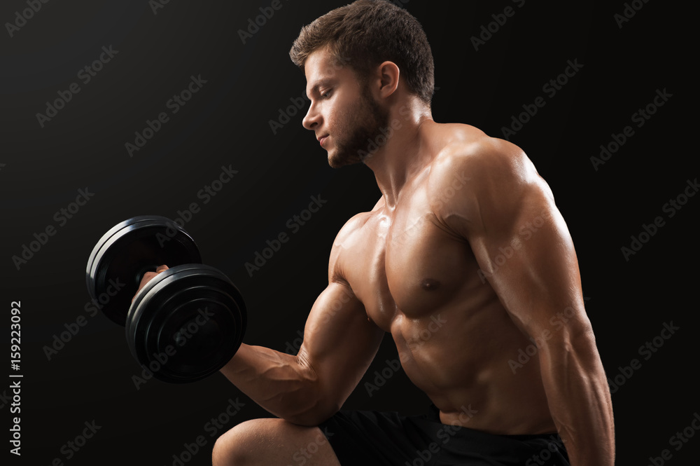 Muscular ripped young man doing biceps exercise lifting dumbbells on black background gym sport athlete determination energy strength power lifestyle gym fitness sexy arms weightlifting bodybuilding.