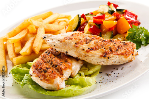 Grilled chicken fillet with french fries on white background