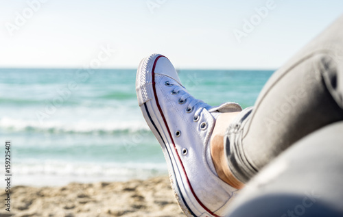 Feet of the woman that is seating by the sea. Picture with blurry background.
