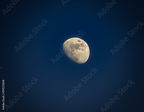 Gibbous moon over dark blue sky seen with a telescope at night. Picture with vignetting.