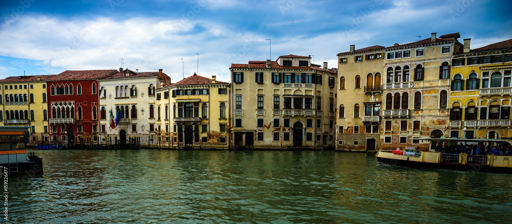 Panoramic view on famous Grand Canal among historic houses in Venice, Italy at cloudy day with dramatic sky. 