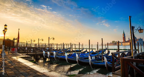Gondolas moored by Saint Mark square in Venice, Italy at sunrise. Picture with sunbeams