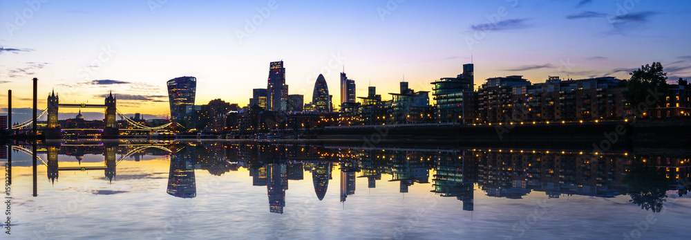 London skyline at dusk including Tower Bridge and skyscrapers at financial district with clear reflection
