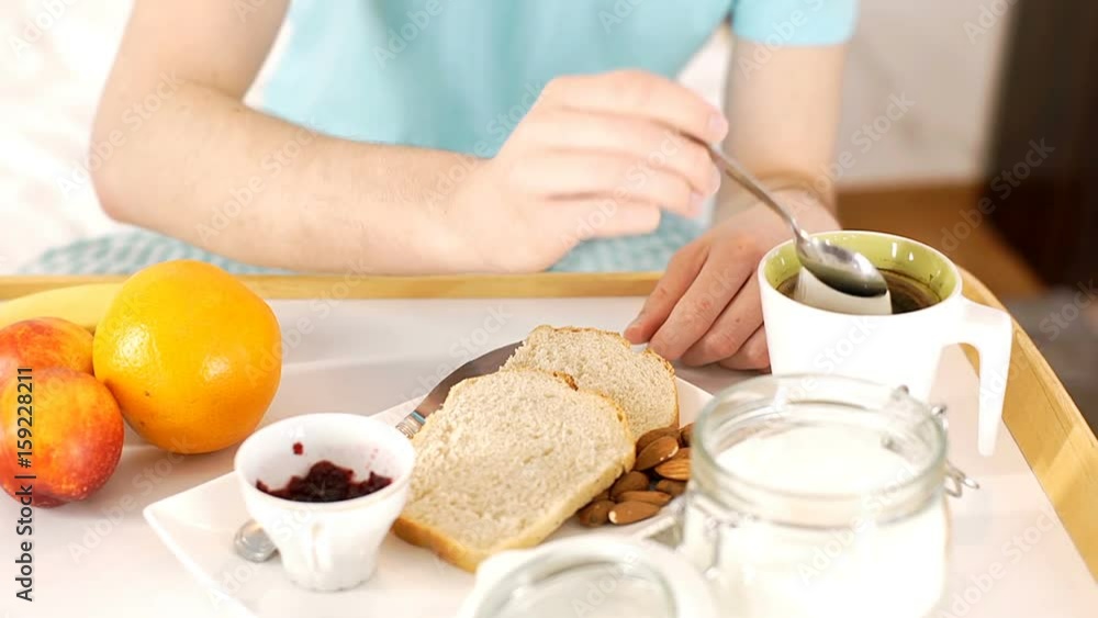 Young man having breakfast in bed and mixing tea, steadycam shot
Young man having breakfast in bed and mixing tea, steadycam shot