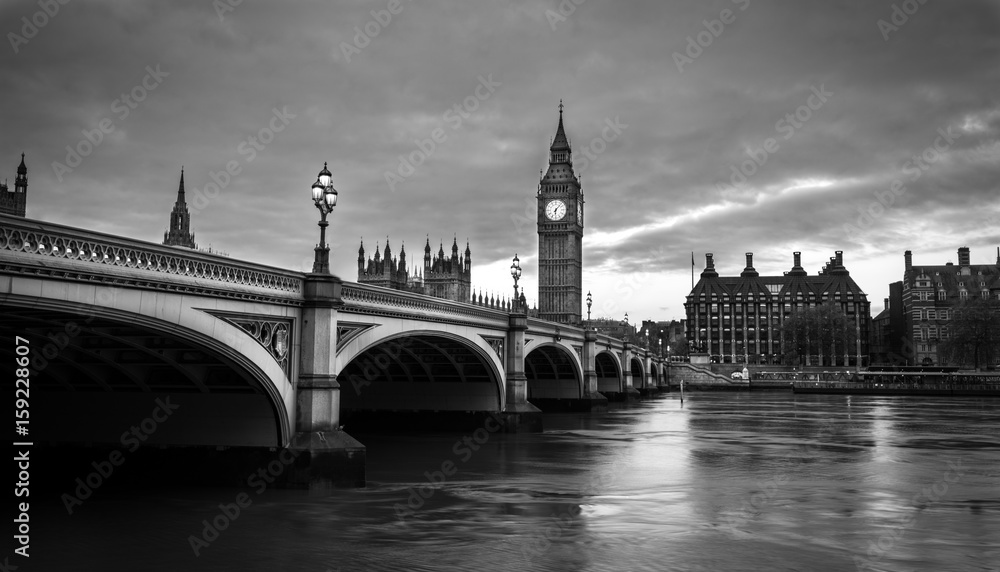 Big Ben and Westminster bridge in London at dusk. Black and white photo with dramatic sky