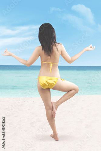 Woman with bikini meditating at beach