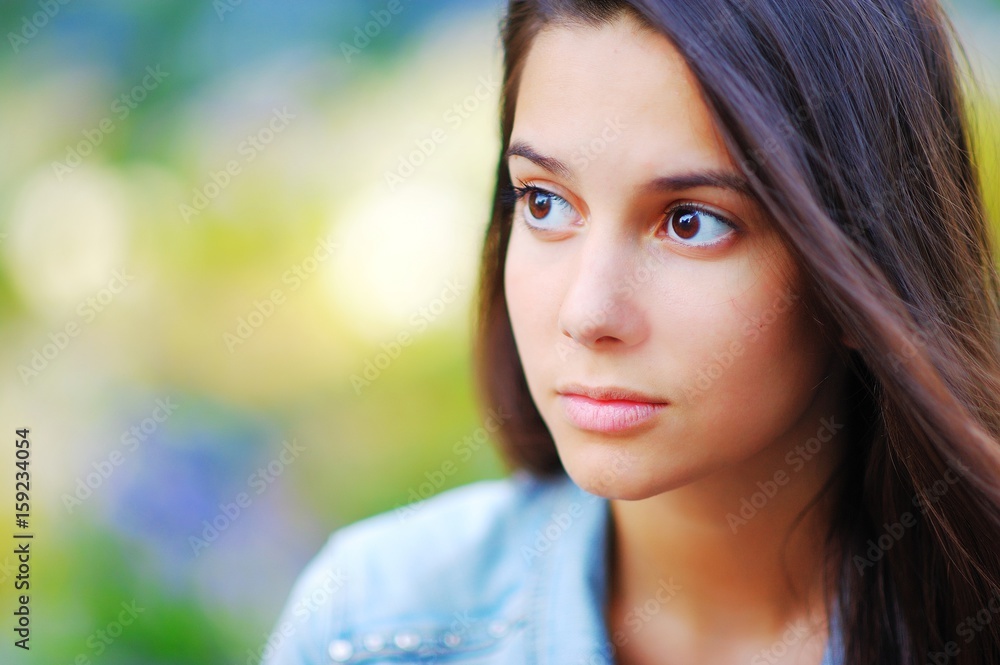 Young pretty brooding brown-eyed woman outdoors portrait. Soft sunny colors, blurred background. Close-up Young pretty brooding brown-eyed woman outdoors portrait. Soft sunny colors, blurred background. Close-up