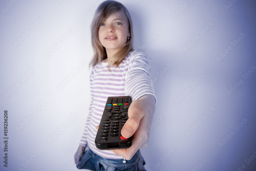Girl using the TV or video remote control and pushing the power button. Focused on the remote control. Girl using the TV or video remote control and pushing the power button. Focused on the remote control.