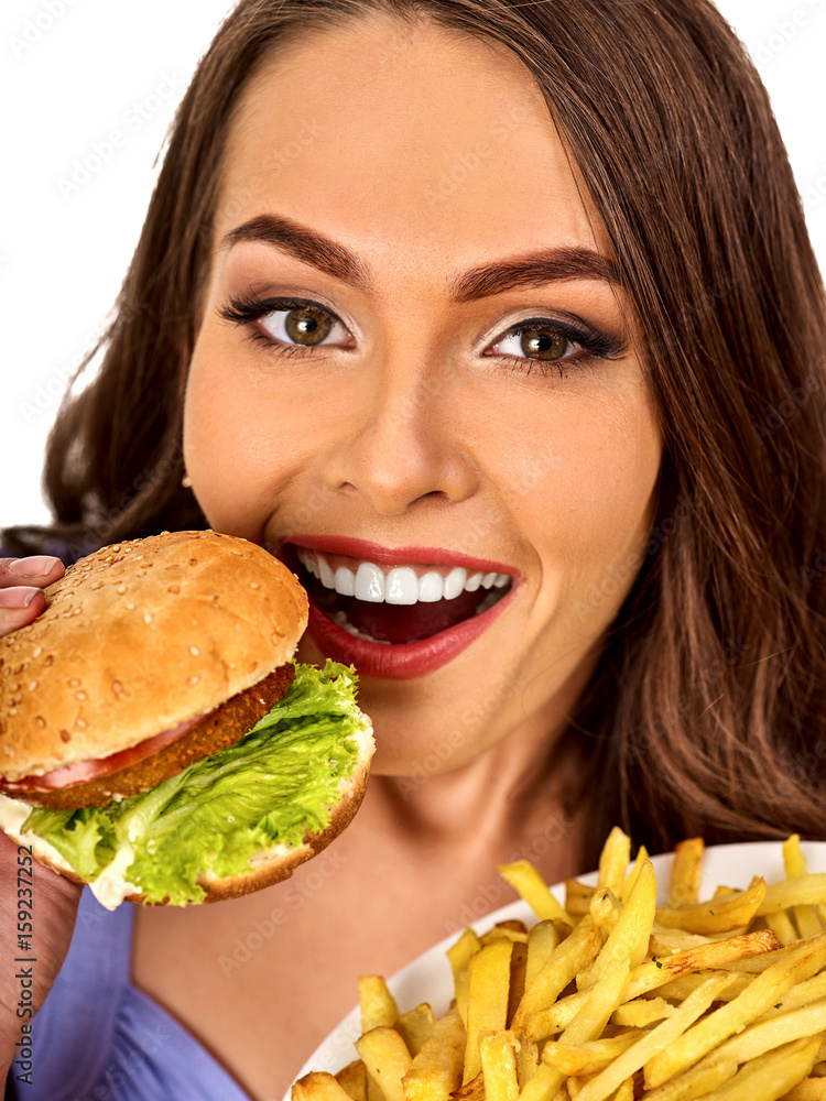 Woman eating french fries and hamburger. Portrait of student consume fast food on table. Girl trying to eat junk. Girl is having supper after hard day's work. Person broke off from diet.