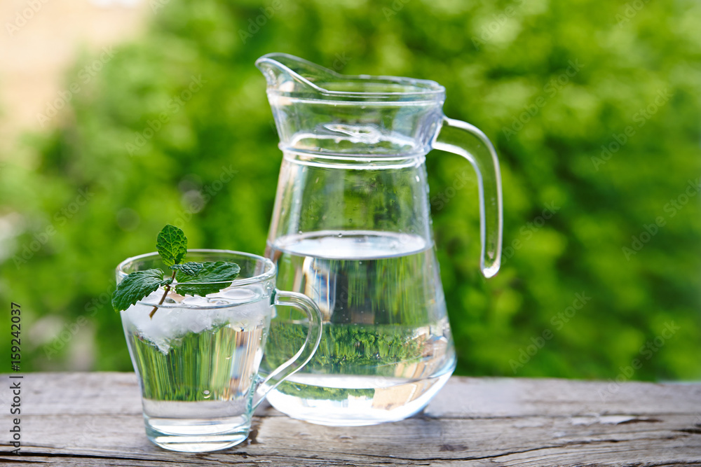 Glass Cup With Ice Water And Mint A Jug Of Water On A Wooden Table Against A Background Of Green Foliage Stock Photo Adobe Stock Glass Cup With Ice Water And Mint A Jug Of Water On A Wooden Table Against A Background Of Green Foliage Stock Photo Adobe Stock