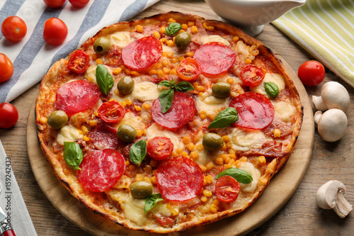 Tasty pizza with ingredients on wooden table