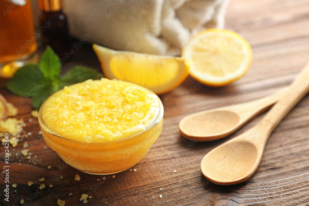 Glass bowl with lemon scrub and spoons on wooden table Glass bowl with lemon scrub and spoons on wooden table