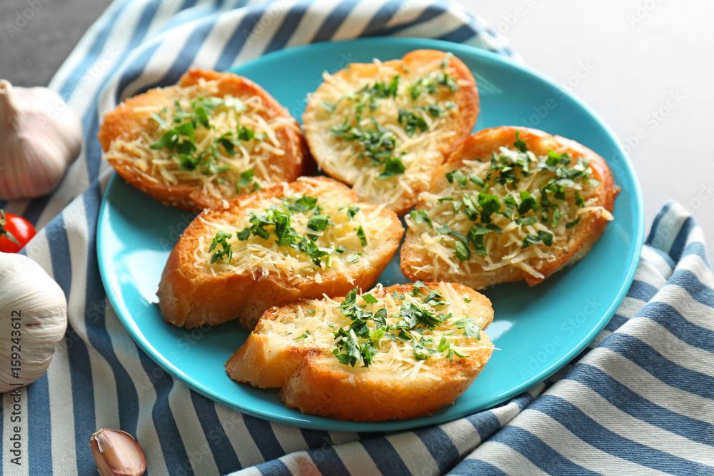 Tasty bread slices with grated cheese, garlic and herbs on plate