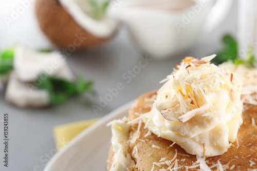 Stack of delicious coconut pancakes with butter cream and shavings, close up