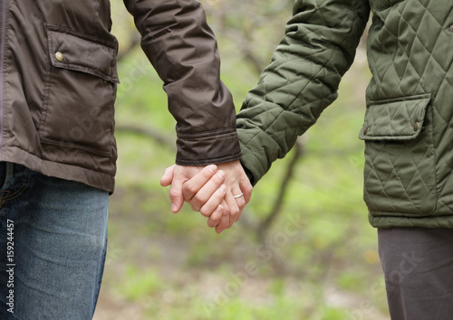 Gay couple holding hands together outdoors, close up