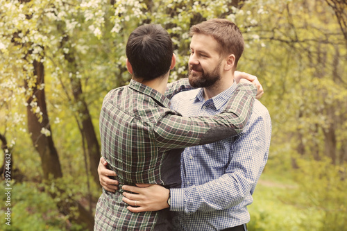 happy gay couple hugging in park