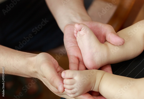 The father held the baby's feet in both hands