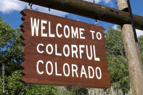 Tilted Welcome to Colorful Colorado sign on a wooden post