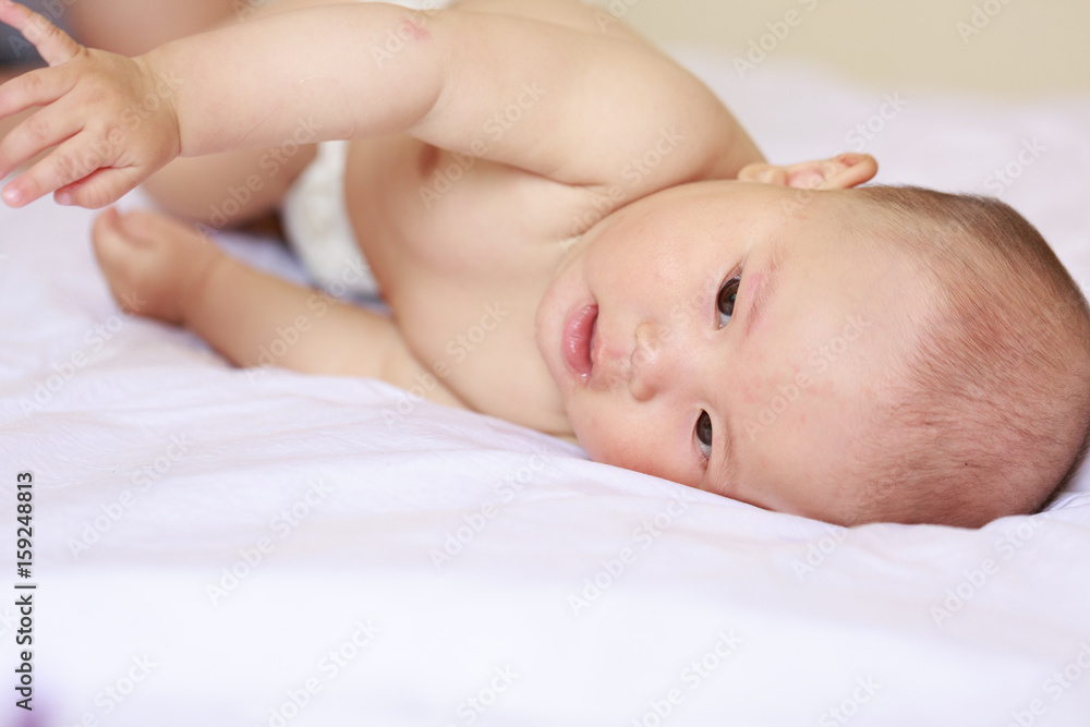 A baby is lying on a white sheet A baby is lying on a white sheet