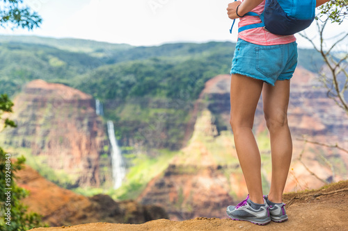 Hiking hiker girl at Waimea Canyon Kauai looking at Waipoo falls Hawaii waterfall. Kauai travel. photo