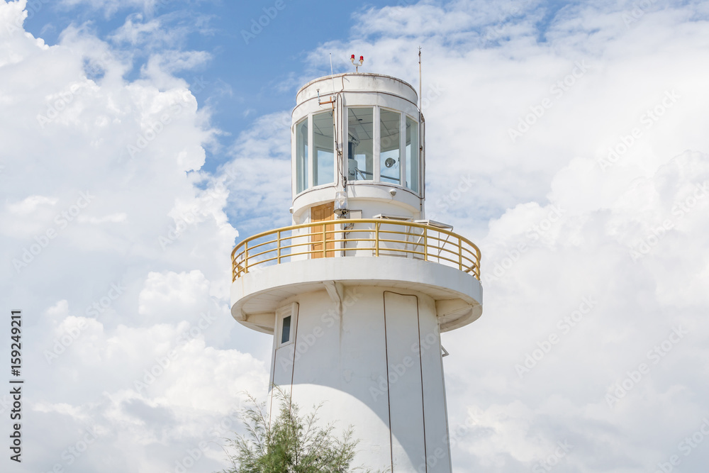 White lighthouse standing under the white fluffy cloudy sky. White lighthouse standing under the white fluffy cloudy sky.