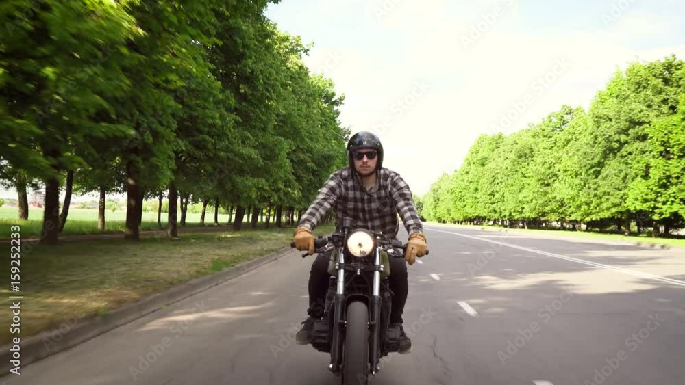 Biker riding a motorcycle on a road surrounded by trees Biker riding a motorcycle on a road surrounded by trees