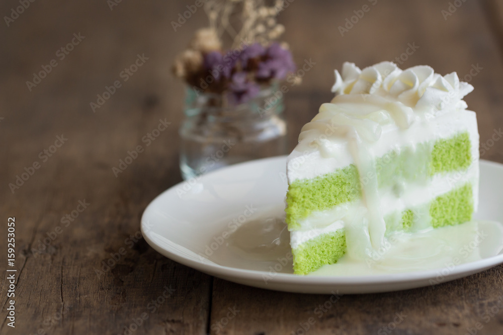 Pandan cake frosting by wipped cream topping with young toddy palm seed in coconut milk sauce on white plate put on wood table. Thai style dessert. Pandan cake frosting by wipped cream topping with young toddy palm seed in coconut milk sauce on white plate put on wood table. Thai style dessert.