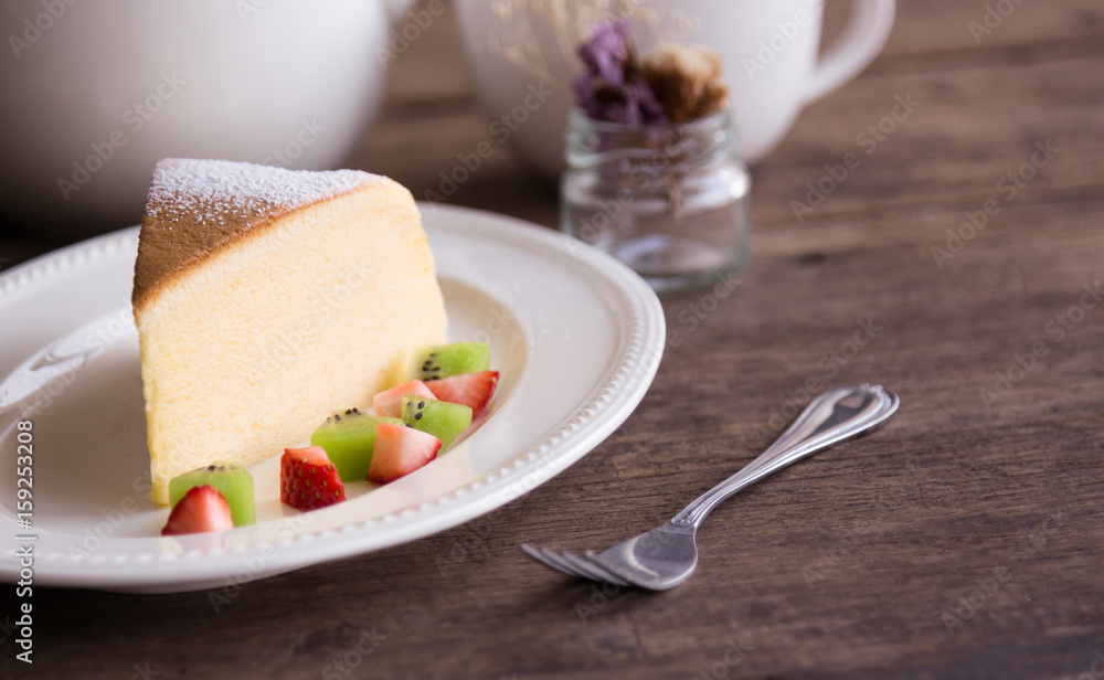Homemade Japanese cheesecake so delicious, fluffy,lite and soft sparkling with  icing, fresh fruit:kiwi and strawberry. Soft cheesecake Japanese style. Souffle cotton cheesecake put on rustic wood.