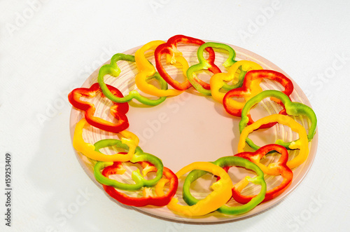 Circles of bell pepper on a ceramic plate on a white background