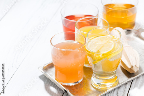 assortment of fresh citrus juices in glasses and white background