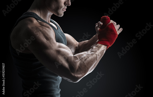 Strong man wrap hands on black background Man is wrapping hands with red boxing wraps isolated on black background Strong hands and fist, ready for training and active exercise © USM Photography