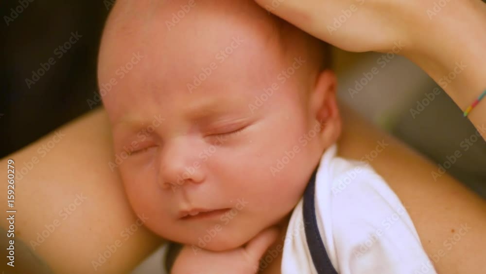 adorable little newborn baby is falls asleep in mother's arms. Close up shot adorable little newborn baby is falls asleep in mother's arms. Close up shot