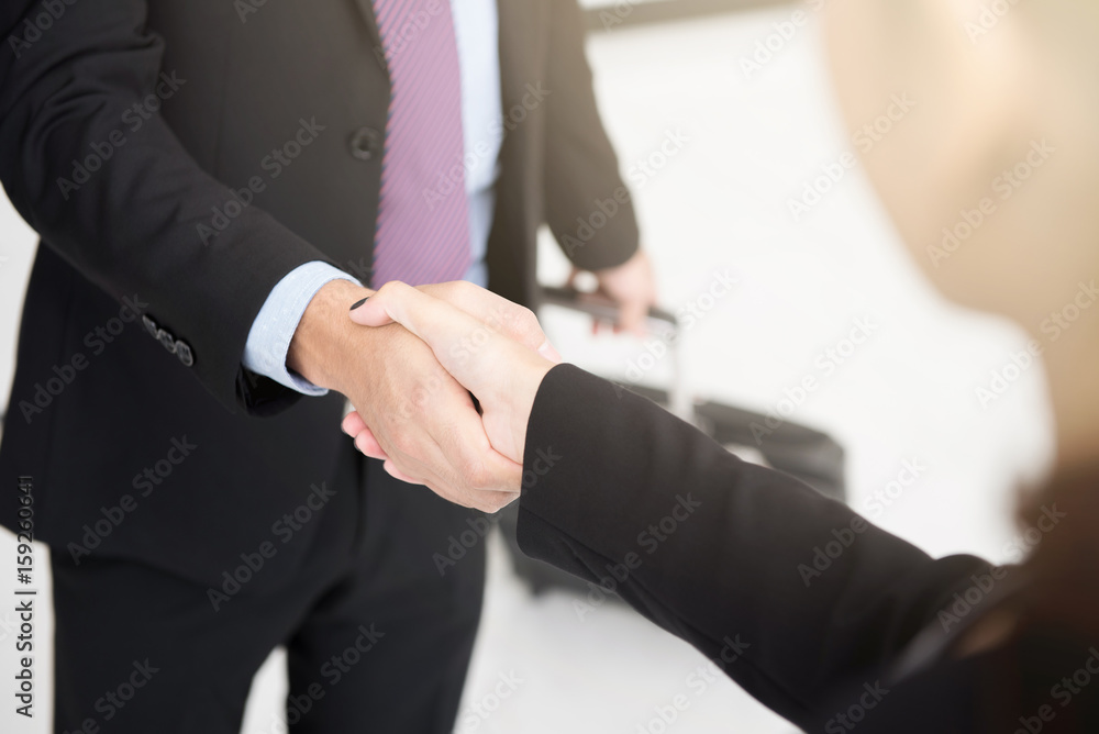 Businessman making handshake while pulling luggage Businessman making handshake while pulling luggage