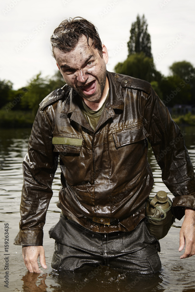 Wet and dirty soldier in uniform after overcoming river